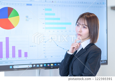 一位年輕的女商人一邊看著顯示器上顯示的文件一邊思考 122393391