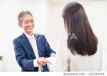A businesswoman being handed a gift by her boss A businesswoman being handed a gift by her boss 122393545
