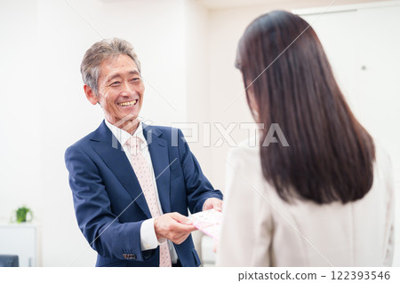 A businesswoman being handed a gift by her boss A businesswoman being handed a gift by her boss 122393546