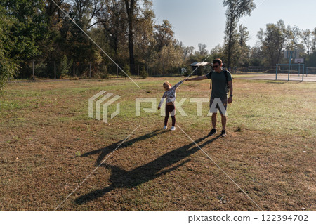 A father and daughter walk hand in hand through a park, enjoying quality time and the beauty of the 122394702