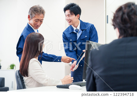 A man in work clothes and a woman in a suit talking in the office A man in work clothes and a woman in a suit talking in the office 122394718