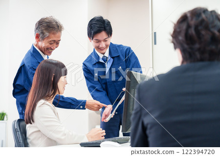 A man in work clothes and a woman in a suit talking in the office A man in work clothes and a woman in a suit talking in the office 122394720