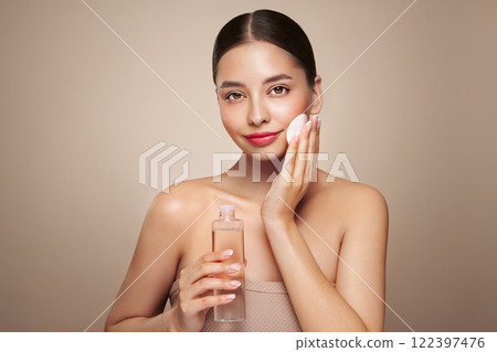 Smiling woman holds bottle with cosmetic tonic 122397476