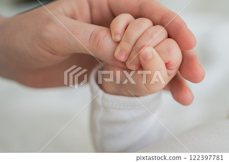 Happy family. Tiny newborn infant baby little hand on mother hand palm. Newborn baby holding parent finger after birth. Mom baby at home. Support protection of new life. Handle with care 122397781