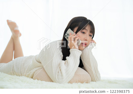 Japanese woman lying face down talking on the phone 122398375