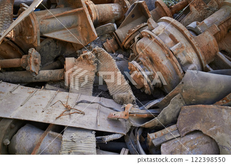 A large and rusty industrial scrap metal pile stacked high with discarded materials and debris. Closeup view showcasing a messy pile of rusted, neglected industrial scrap metal in an outdoor setting 122398550