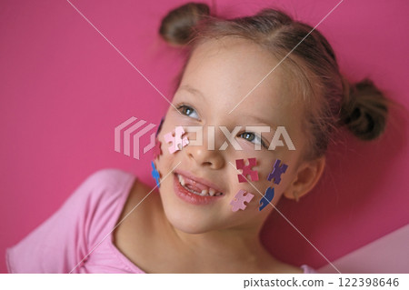 A sweet, thoughtful girl with an autism symbol on her cheek looks away. Support and care as a sign of solidarity 122398646