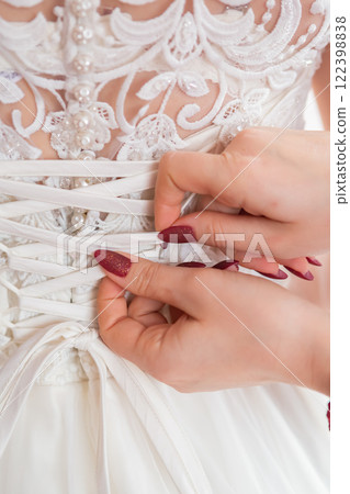 Bridal Gown Lacing Technique at a Wedding Preparation in the Afternoon Sunlight. Bridal Gown Lacing Technique at a Wedding Preparation in the Afternoon Sunlight. 122398838