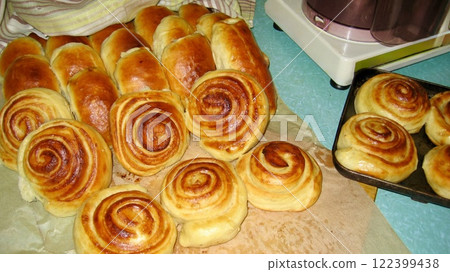 Freshly baked round buns with a golden crust on kraft paper. The warm, appetizing look of the bread evokes a cozy, homemade atmosphere.  122399438