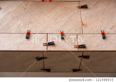 Tile leveling system with plastic clips and wedges, shot while the tile mortar sets. 122399553