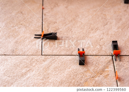 Tile leveling system with plastic clips and wedges, shot while the tile mortar sets. 122399560