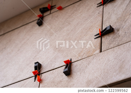 Tile leveling system with plastic clips and wedges, shot while the tile mortar sets. 122399562