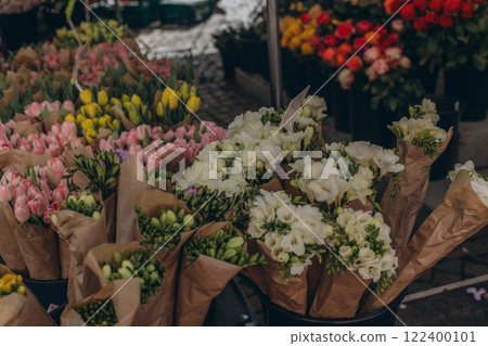 Tulip bouquets for sale at an outdoor market, adding vibrant colors to the lively atmosphere. Tulip bouquets for sale at an outdoor market, adding vibrant colors to the lively atmosphere. 122400101