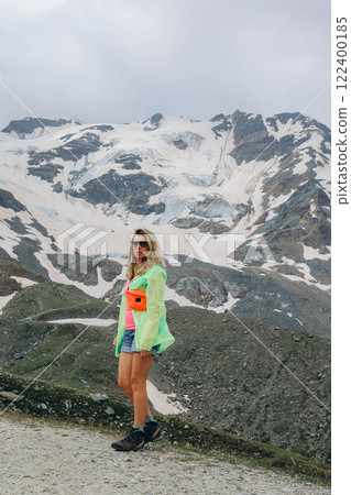 Woman in sports clothes standing standing on a mountain peak and looking up during mountain hike Woman in sports clothes standing standing on a mountain peak and looking up during mountain hike 122400185