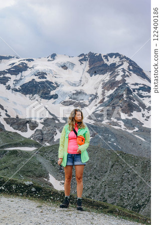 Woman in sports clothes standing standing on a mountain peak and looking up during mountain hike Woman in sports clothes standing standing on a mountain peak and looking up during mountain hike 122400186