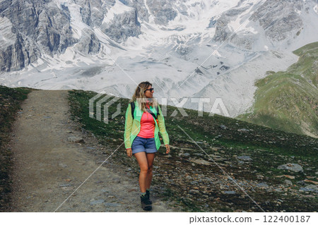 Woman in sports clothes standing standing on a mountain peak and looking up during mountain hike Woman in sports clothes standing standing on a mountain peak and looking up during mountain hike 122400187