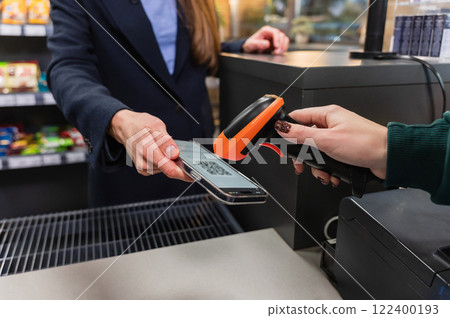 A cashier scans a qr code from a smart phone using a barcode scanner. 122400193