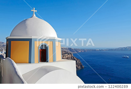 Thira, Santorini island, Greece. View on volcano caldera and Aegean Sea with the white and blue old church of Saint Stylianos on the mountainside in the foreground. Thira, Santorini island, Greece. View on volcano caldera and Aegean Sea with the white and blue old church of Saint Stylianos on the mountainside in the foreground. 122400289