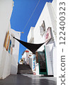 Thira, Santorini island, Greece. Picturesque view of the street of ancient Thira. Traditional white houses against blue sky. 122400323