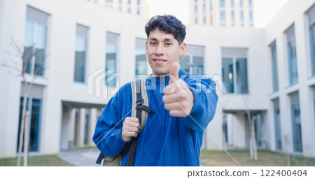 Smiling university student gesturing thumbs up outdoors Smiling university student gesturing thumbs up outdoors 122400404