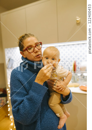 A Mother and Her Baby are Delightfully Enjoying Quality Time Together in a Cozy Kitchen A Mother and Her Baby are Delightfully Enjoying Quality Time Together in a Cozy Kitchen 122400453