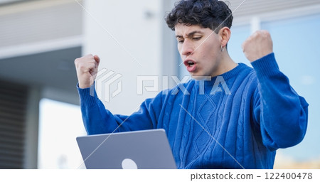 Excited young man celebrating success while working on laptop outdoors 122400478