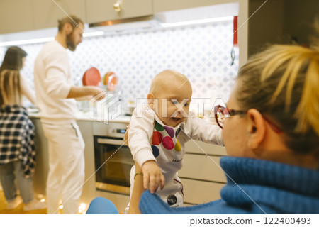 Enjoying beautiful family bonding moments in a cozy, inviting kitchen atmosphere Enjoying beautiful family bonding moments in a cozy, inviting kitchen atmosphere 122400493