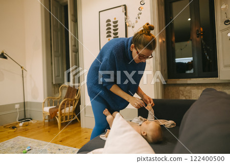 A Caring Mother is Attending to Her Baby in a Cozy Living Room Filled with Comfort and Love A Caring Mother is Attending to Her Baby in a Cozy Living Room Filled with Comfort and Love 122400500