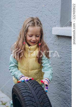 A daughter helps her father change tires on the car, sharing a bonding moment during the task 122400622