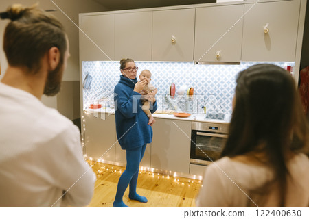 A cozy family gathering featuring a baby is taking place in a modern kitchen setting 122400630