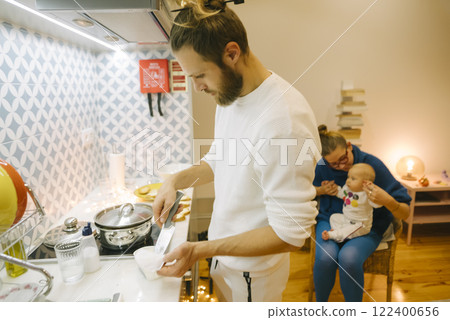 In their cozy kitchen, a happy family cooks together, making warm memories full of joy 122400656