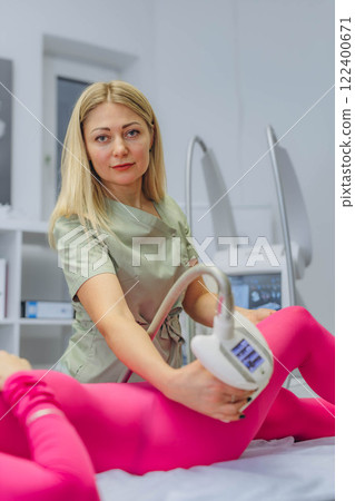 Young woman in a pink suit receiving LPG massage at a professional cosmetology clinic. 122400671