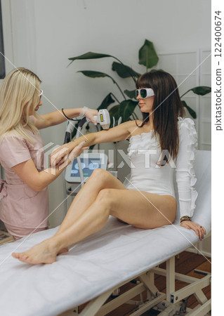 Hair removal procedure.woman client receiving laser hair removal procedure on body in beauty clinic Hair removal procedure.woman client receiving laser hair removal procedure on body in beauty clinic 122400674