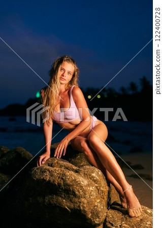 Stunning woman model in bikini on ocean beach. Night shoot with sea in background. Fitness and beauty focus. Perfect for summer, travel, lifestyle themes. Stunning woman model in bikini on ocean beach. Night shoot with sea in background. Fitness and beauty focus. Perfect for summer, travel, lifestyle themes. 122400728