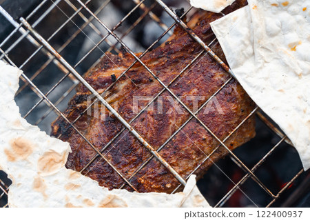 A close-up of perfectly seasoned grilled meat and flatbread on a barbecue grill, ready to be served A close-up of perfectly seasoned grilled meat and flatbread on a barbecue grill, ready to be served 122400937