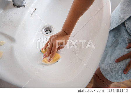 Hand Cleaning a Ceramic Sink Basin with a Sponge at Home 122401143