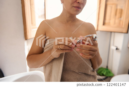 Woman Holding a Beauty Tool While Wrapped in a Towel Woman Holding a Beauty Tool While Wrapped in a Towel 122401147