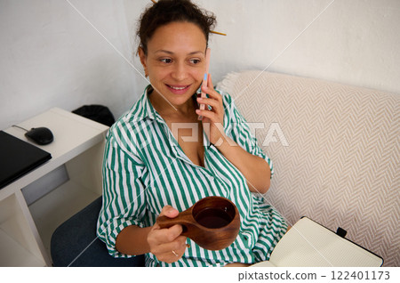 Woman enjoying a conversation while holding coffee in a relaxed environment 122401173