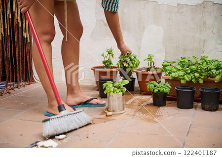 Person tending herb garden while cleaning outdoor tiled patio Person tending herb garden while cleaning outdoor tiled patio 122401187
