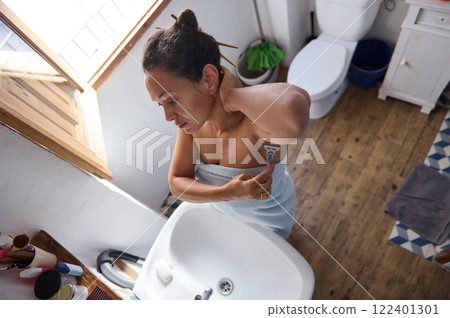 Woman Shaving Armpits in a Bright Bathroom Morning Routine 122401301