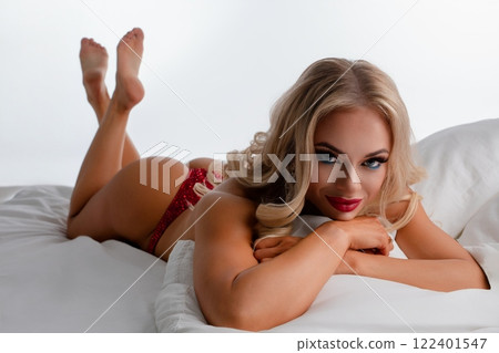Woman poses in fitness lingerie on bed showcasing her athletic physique Woman poses in fitness lingerie on bed showcasing her athletic physique 122401547