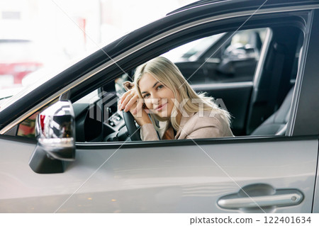 Happy business woman sitting in new car at dealership showroom Happy business woman sitting in new car at dealership showroom 122401634