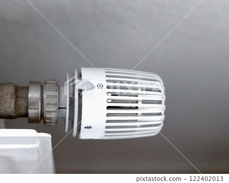 Heating battery temperature regulation in house with thermostat on white radiator. Heating battery temperature regulation in house with thermostat on white radiator. 122402013