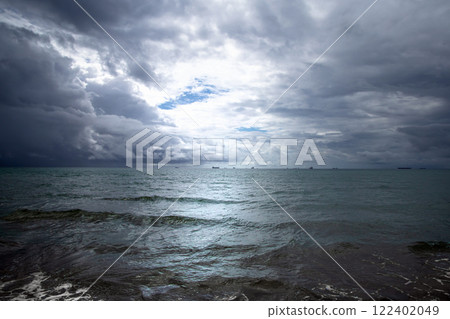 Beautiful dark evening sea and sky with dark clouds through which light passes. 122402049