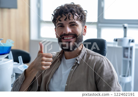 Man smiling to camera sitting in dental chair showing like gesture Man smiling to camera sitting in dental chair showing like gesture 122402191