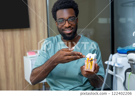 Experienced male dentist orthodontist in medical office showing dental model during consultation 122402206
