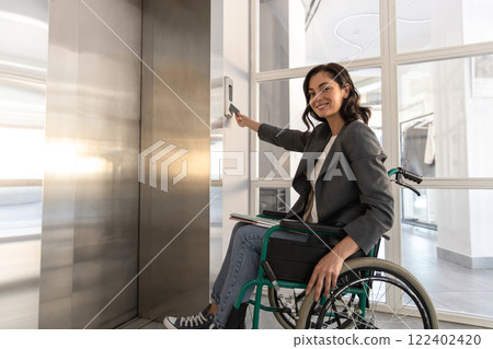 Female entrepreneur with disabilities in wheel chair waiting for elevator in office at work 122402420