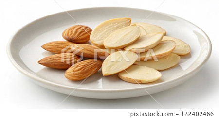 A charming arrangement of sliced almonds their pale nutty color and smooth surfaces spread across a plain white plate.. 122402466