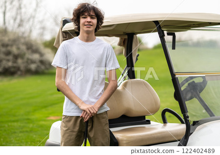 Confident young golfer near the golf cart looking determined Confident young golfer near the golf cart looking determined 122402489