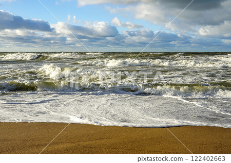 Scenic Baltic sea coastal seascape, stormy sea with big waves, cloudy dark sky, sandy beach 122402663